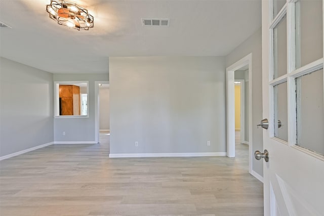 empty room featuring baseboards, visible vents, and light wood-style floors