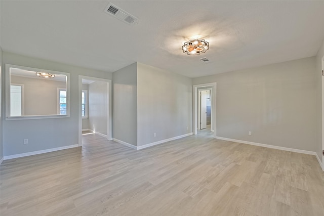 empty room with visible vents, baseboards, and light wood-type flooring