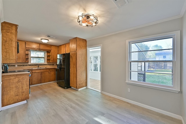 kitchen with backsplash, visible vents, brown cabinetry, and black fridge with ice dispenser