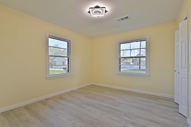 unfurnished bedroom featuring baseboards, visible vents, multiple windows, and light wood-type flooring