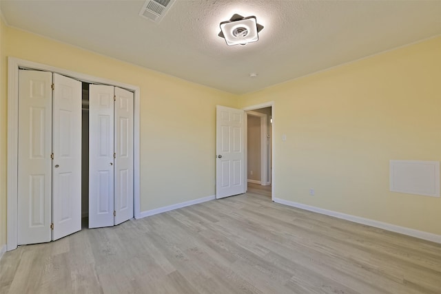 unfurnished bedroom with visible vents, a closet, baseboards, a textured ceiling, and light wood-style flooring
