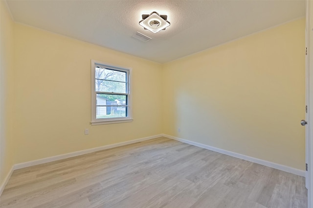 spare room with light wood-type flooring, baseboards, and visible vents