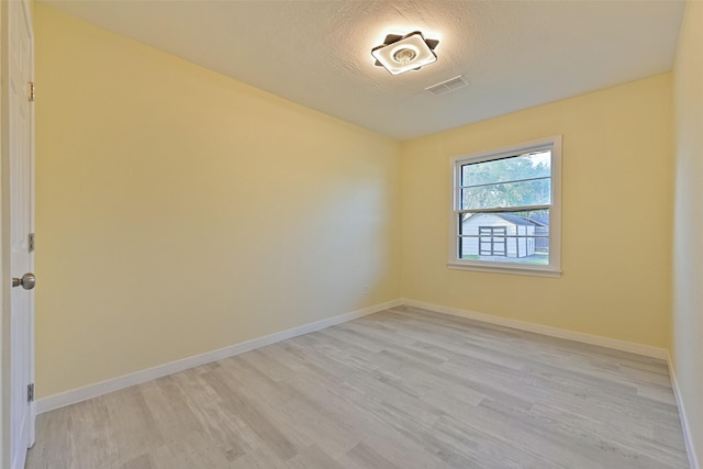 spare room with visible vents, light wood-style flooring, and baseboards