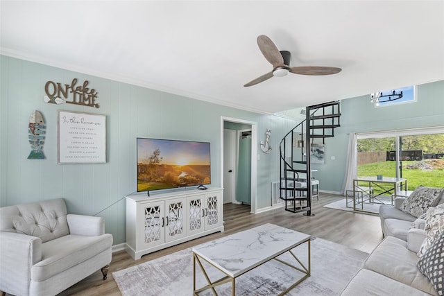 living area featuring baseboards, stairway, ceiling fan, and wood finished floors