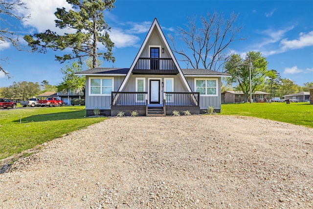 a-frame home featuring a porch, board and batten siding, gravel driveway, and a front yard
