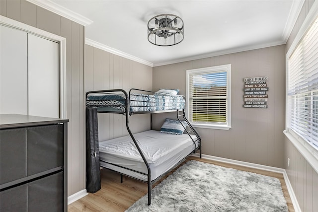 bedroom with crown molding, light wood-style floors, and baseboards