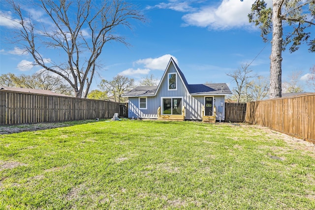 back of house featuring a fenced backyard, entry steps, board and batten siding, and a yard