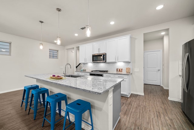 kitchen with a sink, tasteful backsplash, a breakfast bar, dark wood finished floors, and stainless steel appliances