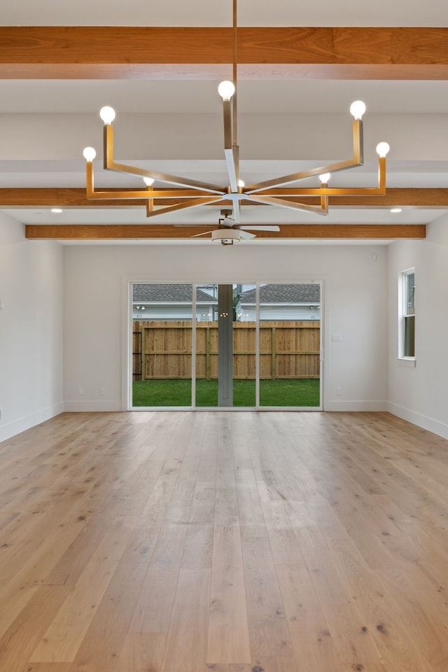 empty room featuring baseboards, wood finished floors, and beamed ceiling