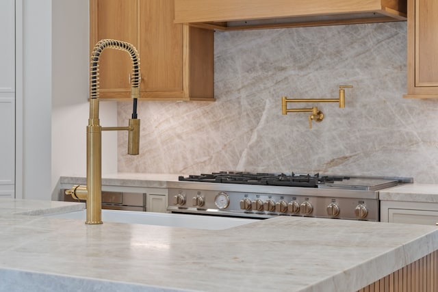 room details with stove, light stone countertops, and decorative backsplash