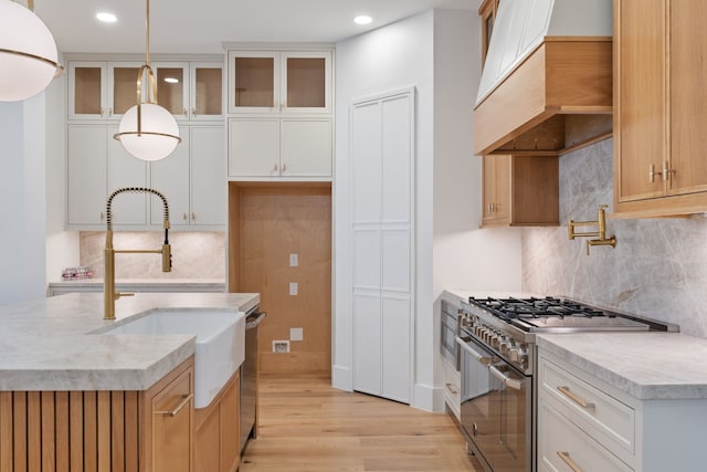 kitchen featuring light wood-type flooring, custom range hood, backsplash, appliances with stainless steel finishes, and recessed lighting