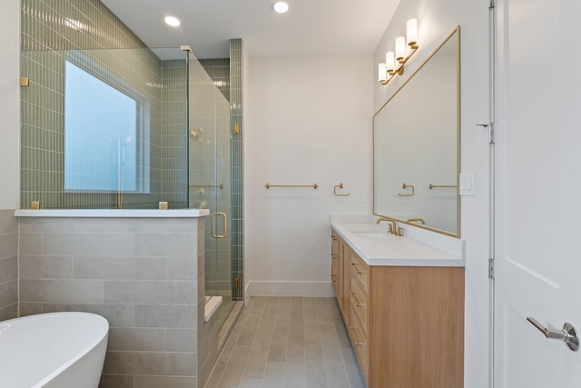 bathroom featuring a soaking tub, a stall shower, baseboards, recessed lighting, and vanity