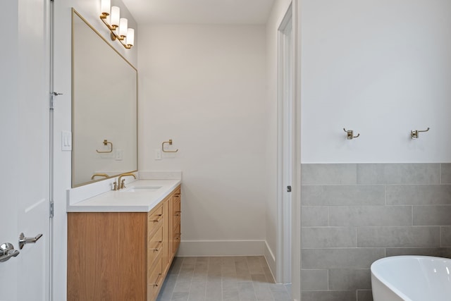 bathroom with vanity, a freestanding tub, and tile walls