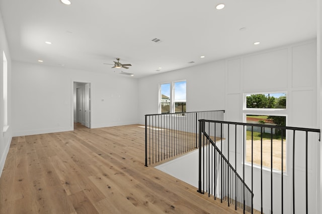hallway featuring recessed lighting, visible vents, light wood finished floors, and an upstairs landing