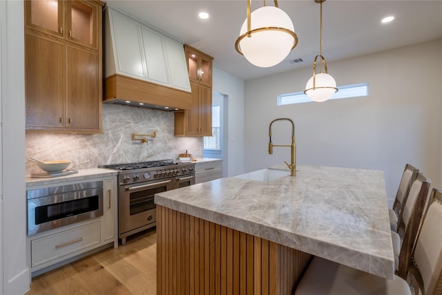 710 Waverly St Unit D, Houston, TX 77007 - kitchen featuring stainless steel appliances, custom exhaust hood, light wood-style floors, tasteful backsplash, and pendant lighting