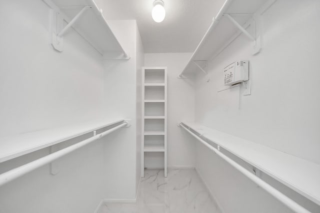 walk in closet featuring marble finish floor