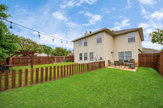 back of house with a chimney, a fenced backyard, a yard, and a patio area