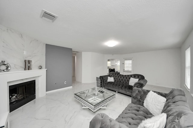 living area with a textured ceiling, a high end fireplace, marble finish floor, visible vents, and arched walkways