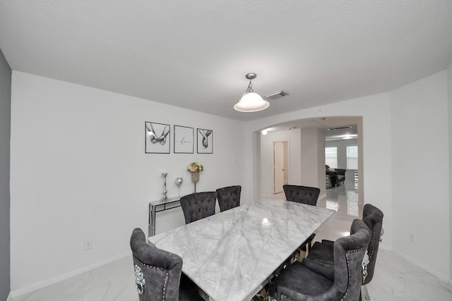 dining room with marble finish floor, arched walkways, baseboards, and visible vents