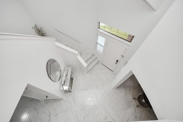 foyer entrance with a high ceiling, marble finish floor, and stairs