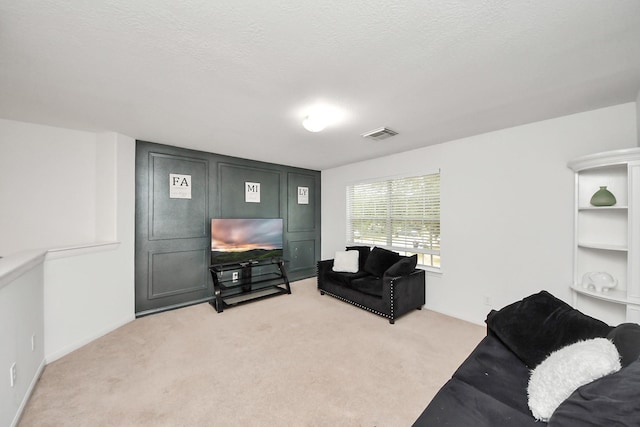 living area featuring a textured ceiling, visible vents, and light colored carpet