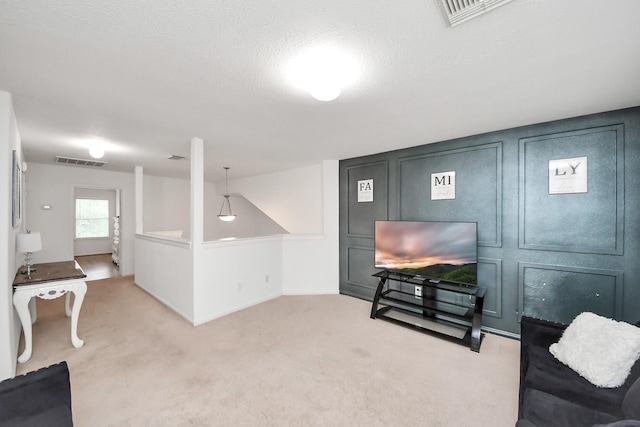 living area with carpet, a textured ceiling, and visible vents