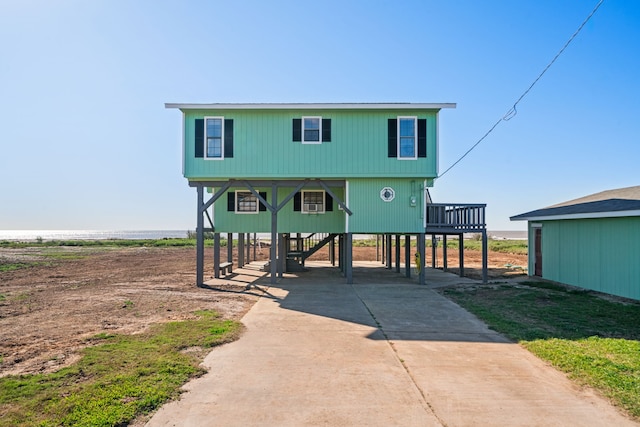 coastal inspired home featuring stairs, concrete driveway, and a carport
