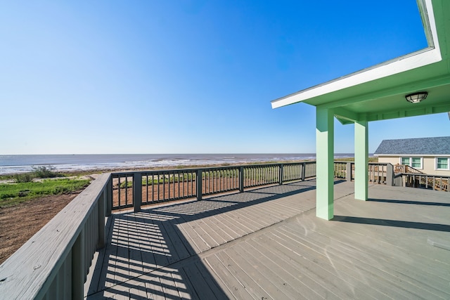 wooden terrace featuring a beach view and a water view