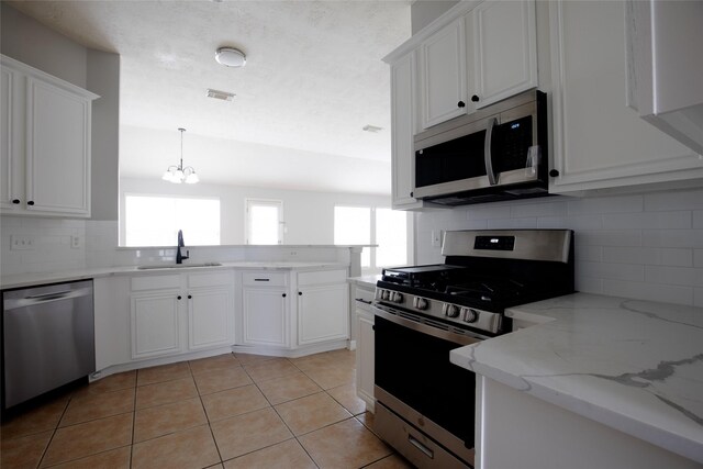 kitchen featuring a sink, appliances with stainless steel finishes, a healthy amount of sunlight, and a peninsula