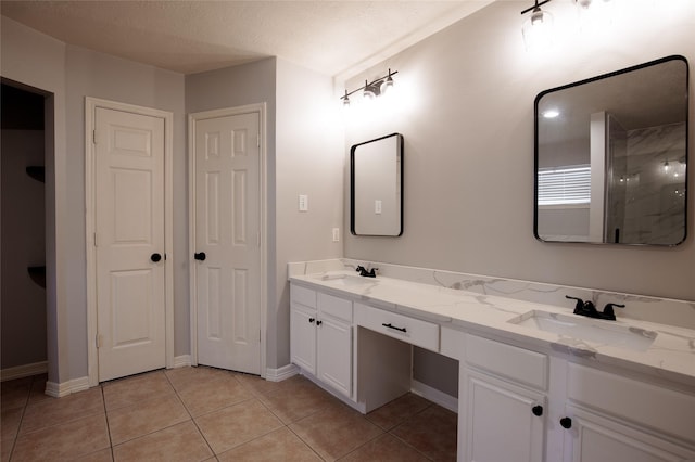 bathroom featuring double vanity, baseboards, a sink, and tile patterned flooring