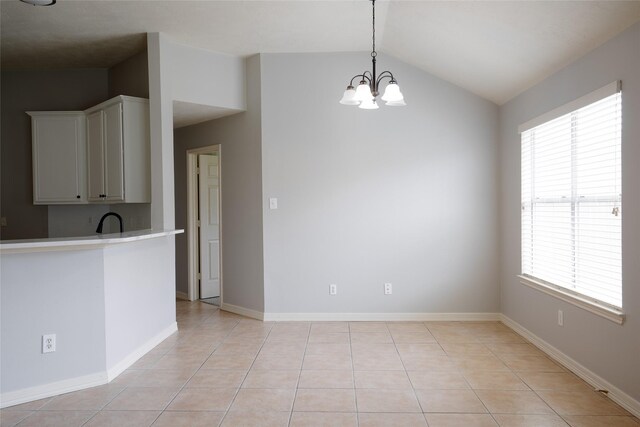 kitchen featuring plenty of natural light, light countertops, a chandelier, lofted ceiling, and light tile patterned flooring