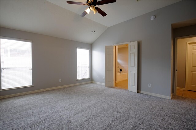 unfurnished bedroom featuring vaulted ceiling, multiple windows, and carpet