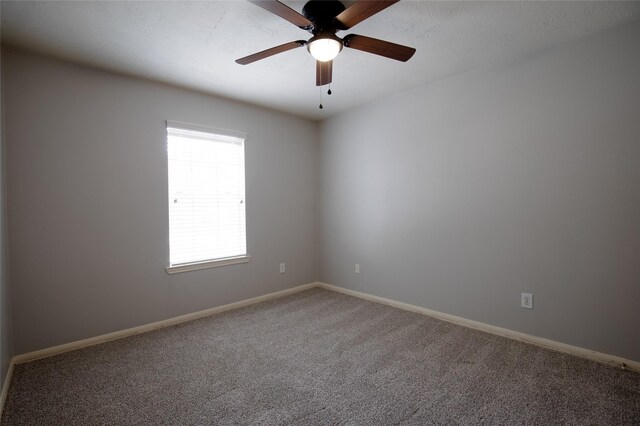 carpeted spare room featuring baseboards and ceiling fan