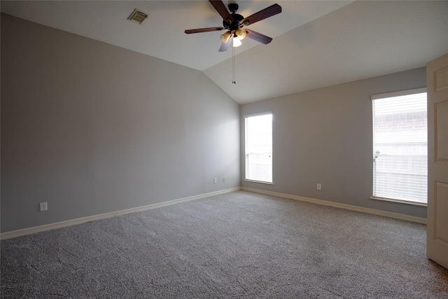 carpeted empty room with a ceiling fan, baseboards, visible vents, and lofted ceiling