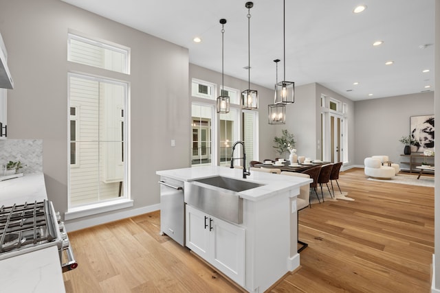 1177 W 19th St, Houston, TX 77008 - kitchen featuring a sink, stainless steel appliances, light wood-type flooring, a center island with sink, and white cabinetry