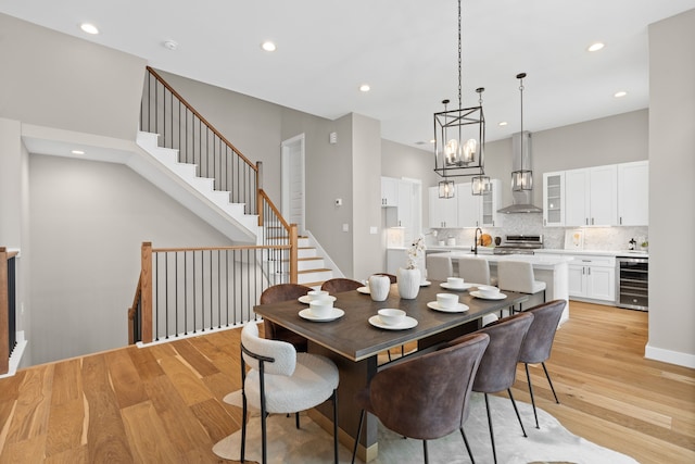 1177 W 19th St, Houston, TX 77008 - dining area with wine cooler, a notable chandelier, recessed lighting, stairway, and light wood-style floors