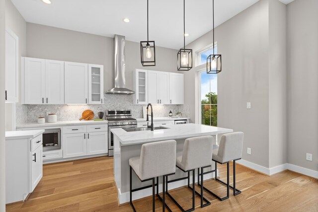 1177 W 19th St, Houston, TX 77008 - kitchen featuring a sink, gas range, backsplash, wall chimney range hood, and a center island with sink