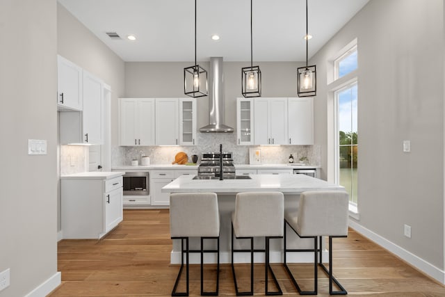1193 W 19th St, Houston, TX 77008 - kitchen with appliances with stainless steel finishes, wall chimney range hood, decorative backsplash, a center island, and recessed lighting