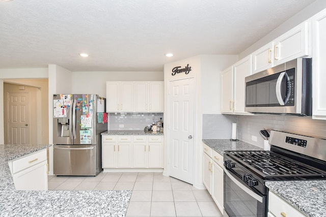 kitchen featuring white cabinetry, light tile patterned floors, decorative backsplash, light stone countertops, and appliances with stainless steel finishes