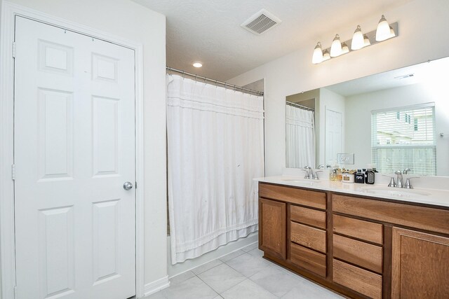 full bath featuring tile patterned flooring, a sink, double vanity, and visible vents