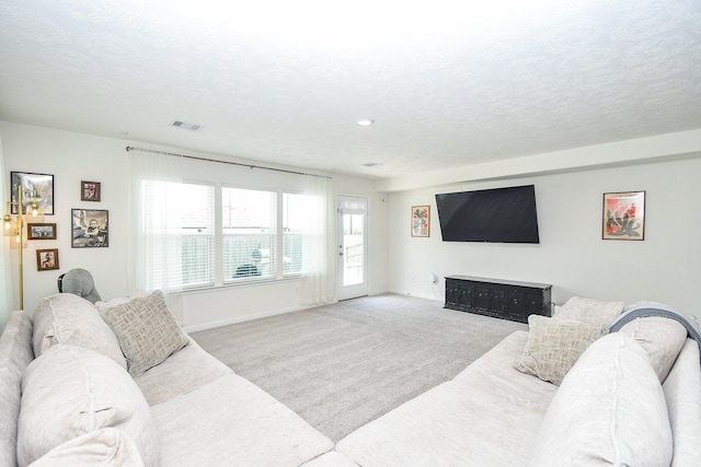 living room with carpet, baseboards, a textured ceiling, and visible vents