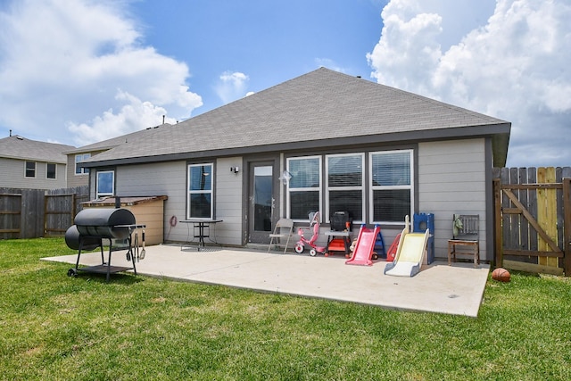 rear view of house featuring fence, a patio, a gate, a shingled roof, and a lawn