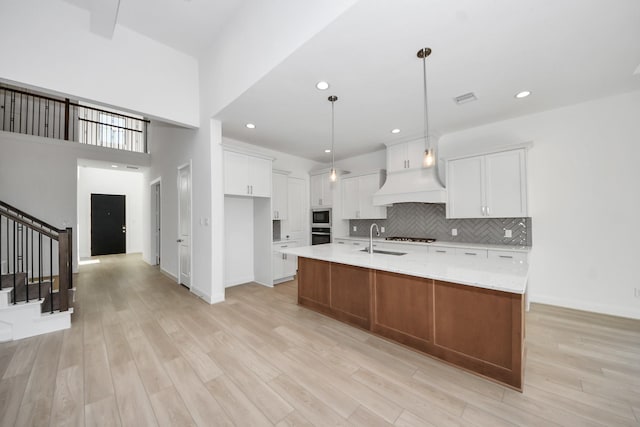 21123 Flowerhorn Dr, Cypress, TX 77433 - kitchen with custom range hood, backsplash, white cabinets, light wood-type flooring, and built in microwave