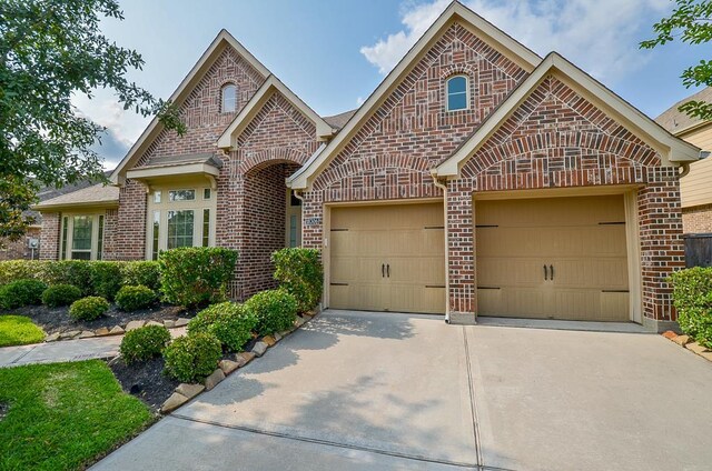 french country inspired facade with driveway, a garage, and brick siding
