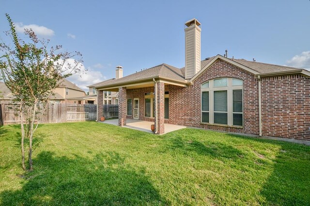 back of property with fence, a chimney, a patio, and a yard