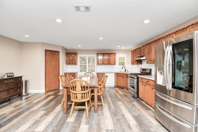20202 Deer Run Rd, Damon, TX 77430 - kitchen with visible vents, light wood-type flooring, under cabinet range hood, a sink, and appliances with stainless steel finishes