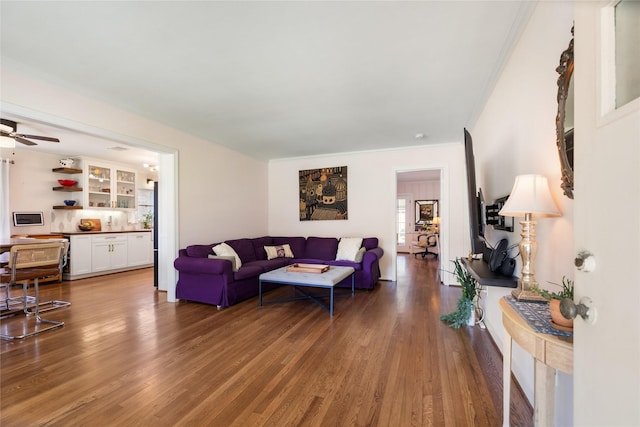 living room with crown molding, ceiling fan, and wood finished floors