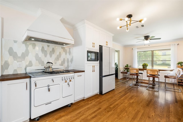 6625 Fairfield St, Houston, TX 77023 - kitchen with freestanding refrigerator, stove, custom exhaust hood, black microwave, and ornamental molding