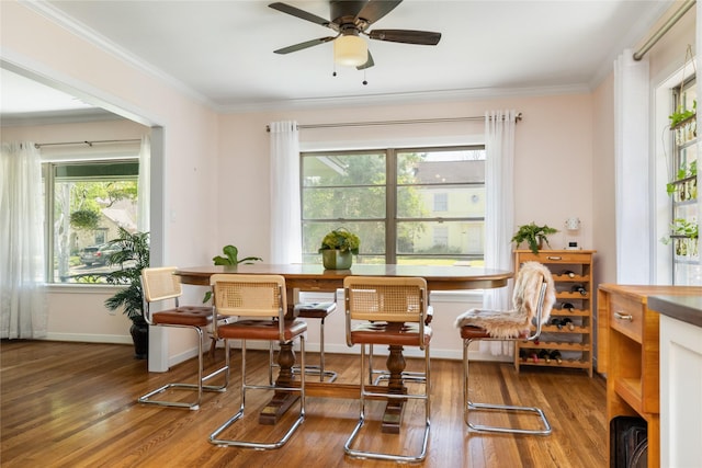 living area featuring baseboards, ornamental molding, a ceiling fan, and hardwood / wood-style flooring