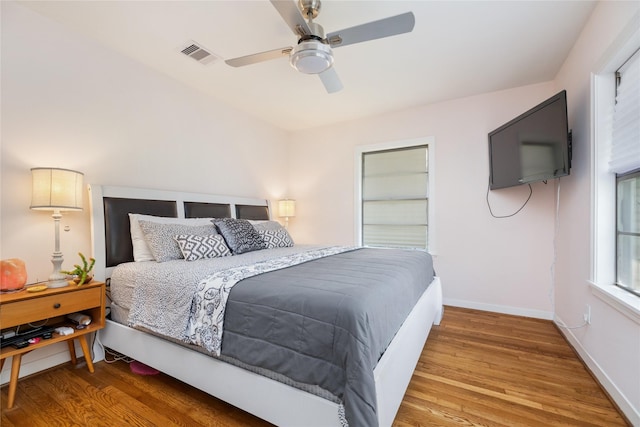 bedroom featuring ceiling fan, baseboards, visible vents, and wood finished floors